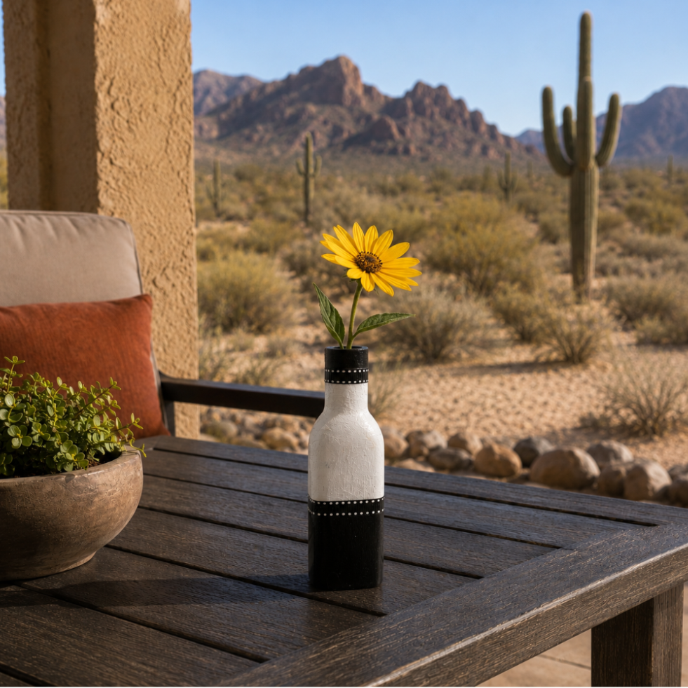 Bud vase with a sunflower on a wooden table in a desert setting
