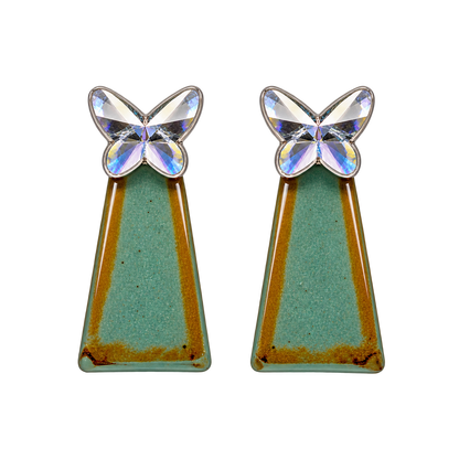 a faceted silver-colored butterfly with a teal-green geometric drop accented with warm golden tones